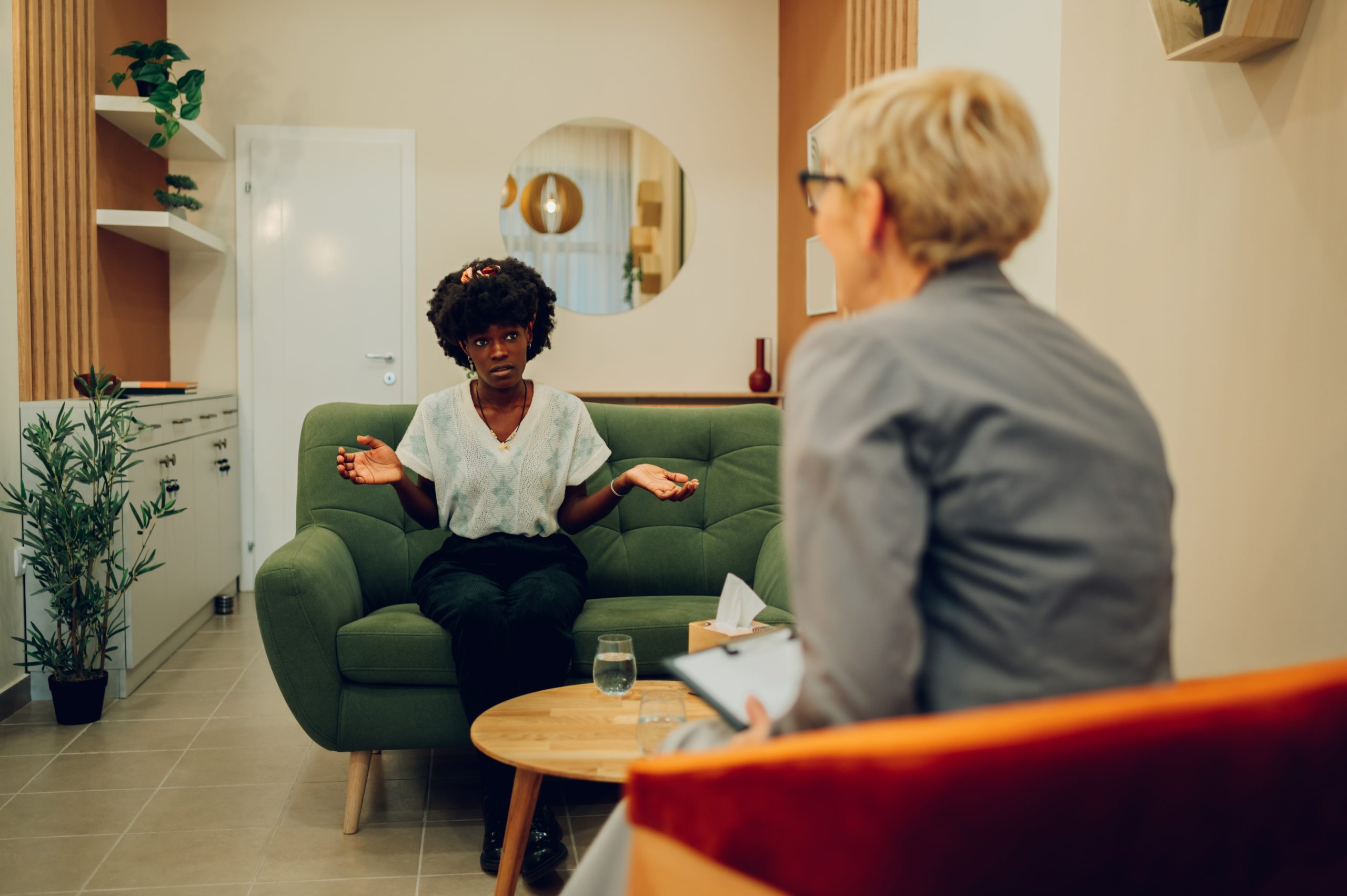 A multiracial woman is sitting in the office with her psychotherapist and talking about issues with her family. Mental health awareness day. A woman is discussing with a psychotherapist at the clinic.